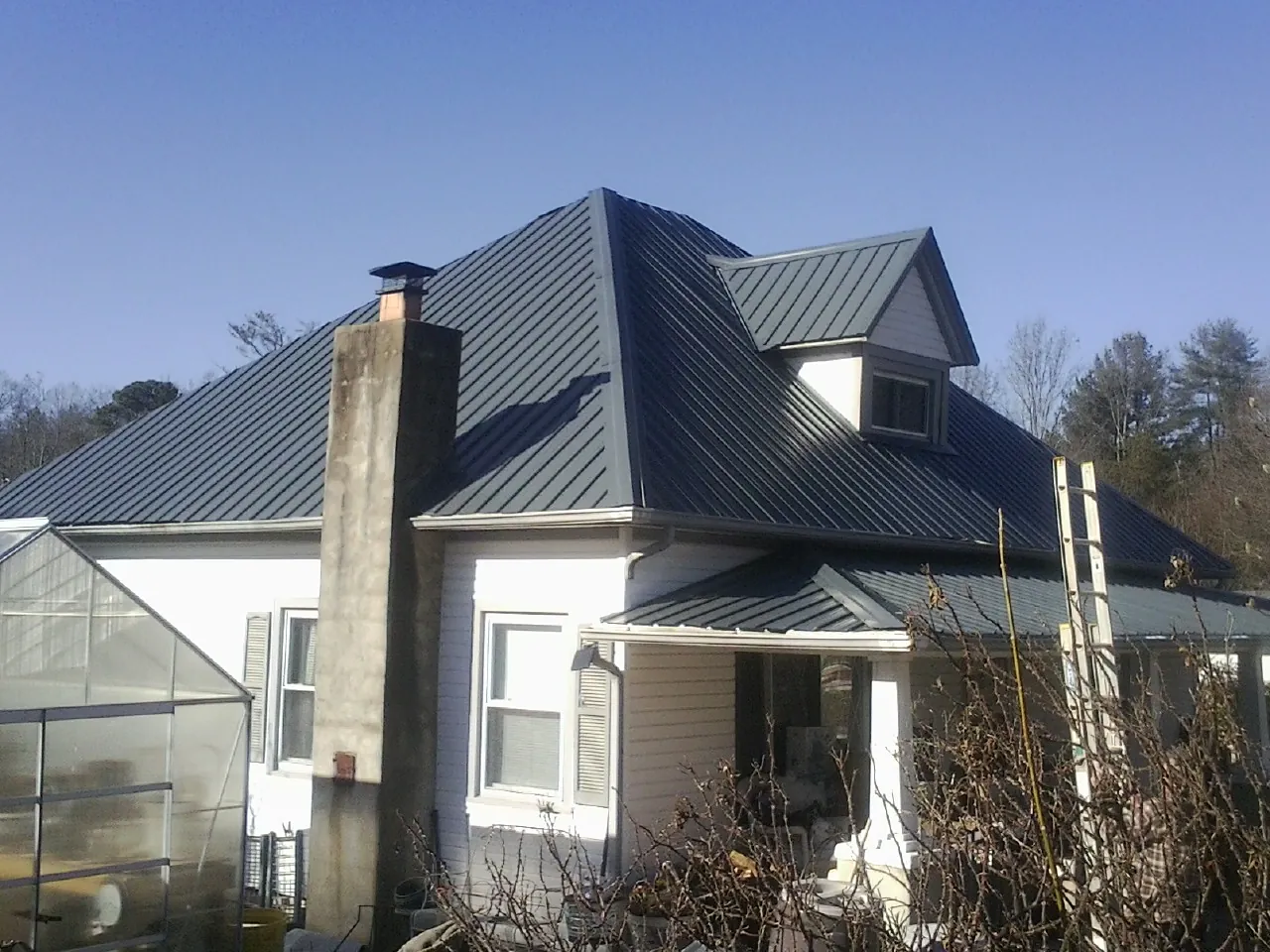 Dark blue standing seam metal roof on a white farmhouse with dormer — Slate & Tile Roof Repair by Roofing Brothers in Schiller Park