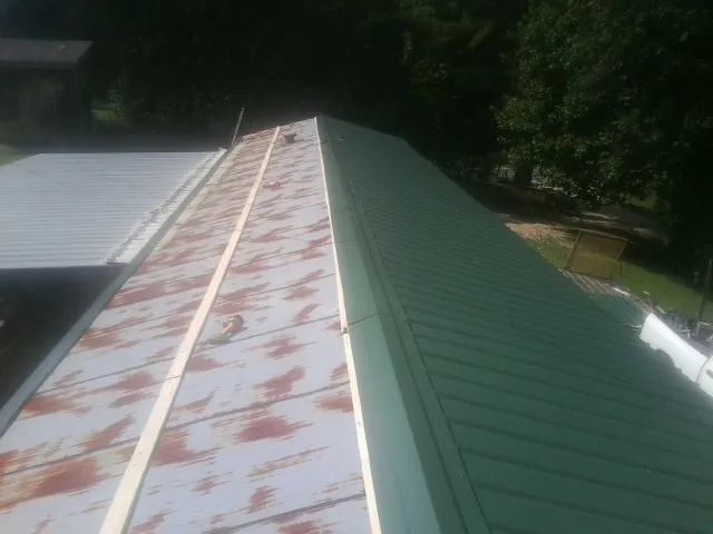 Old rusted panels beside newly installed green metal roofing — Wind Damage Roof Repair by Roofing Brothers in Schiller Park
