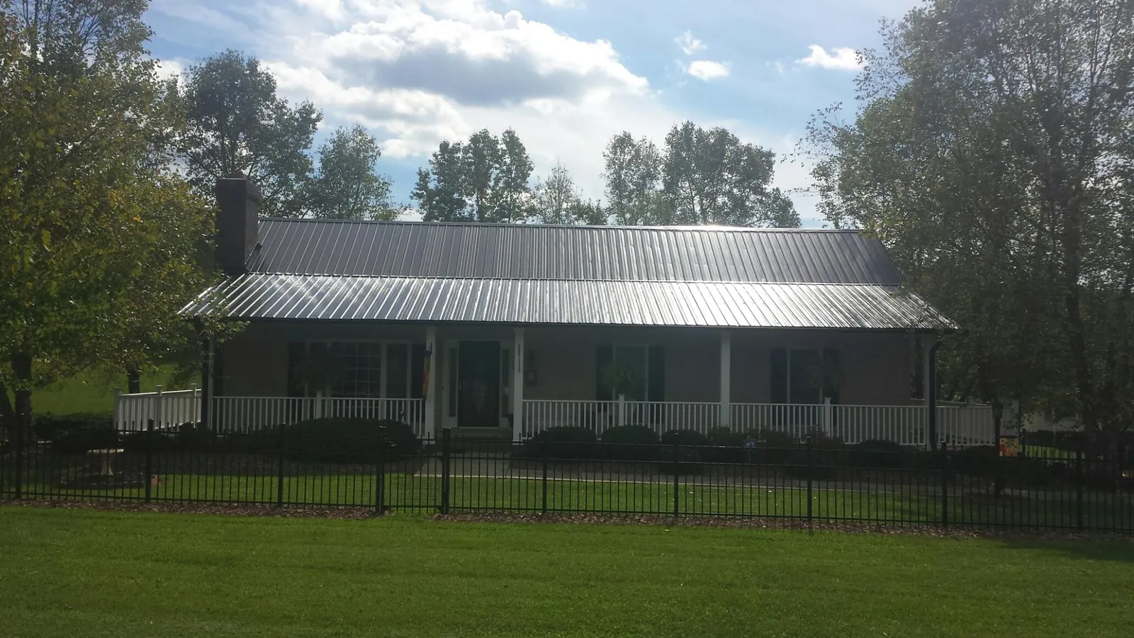 Gray metal roof on a brick ranch with a full width front porch — Gutter Guard Installation work by our crew in Schiller Park