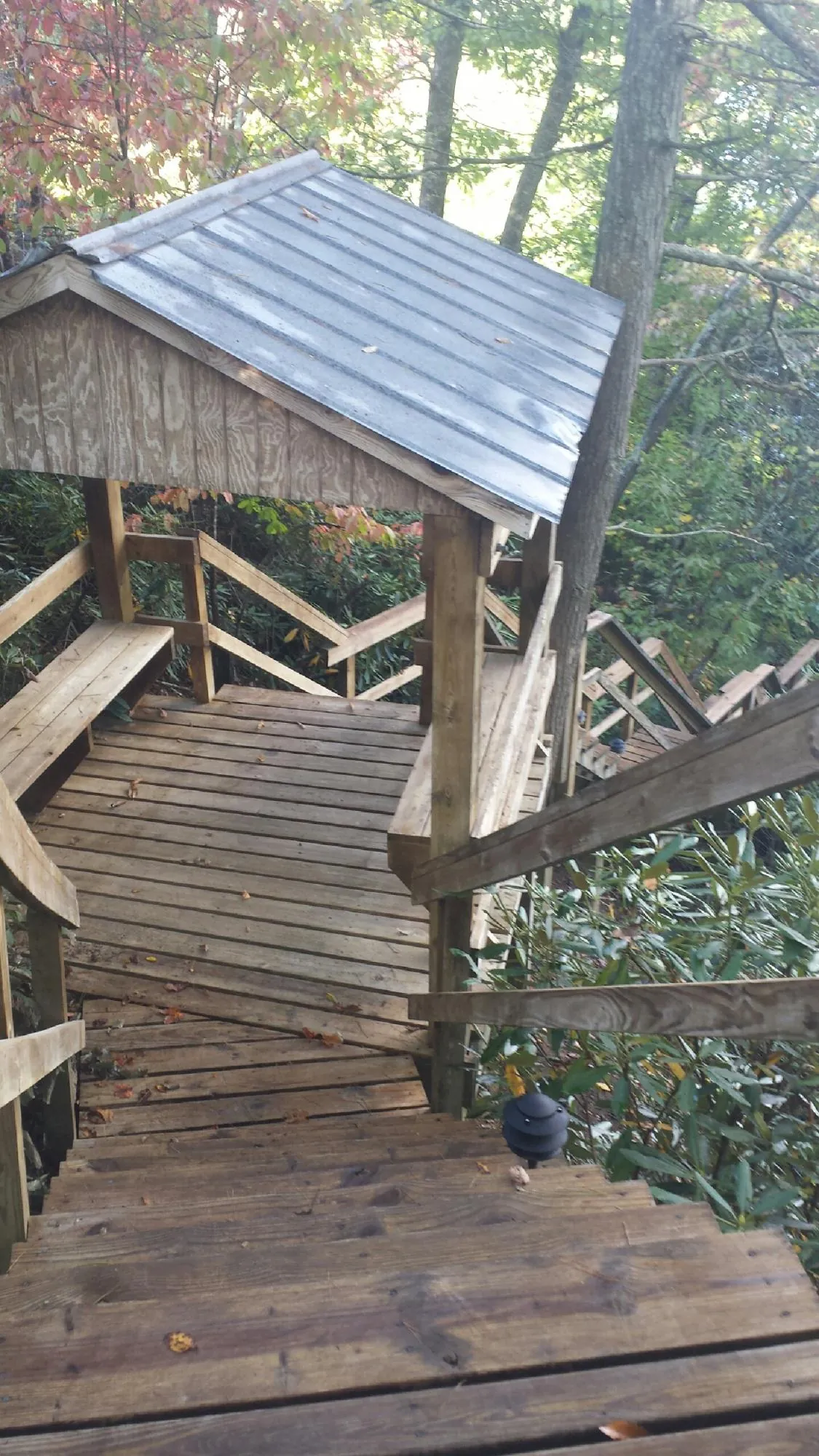 Metal roofed shelter over wooden steps on a wooded walkway — Skylight Repair & Installation work by our crew in Schiller Park