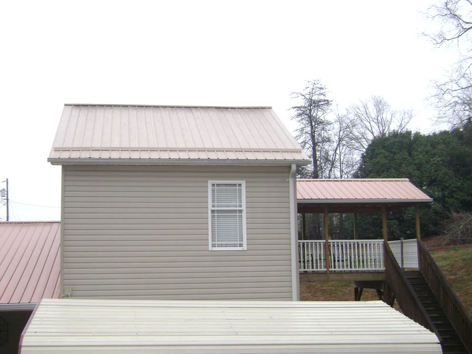 Tan metal roofs on a two story addition and attached porch, from a Roof Replacement job in Schiller Park