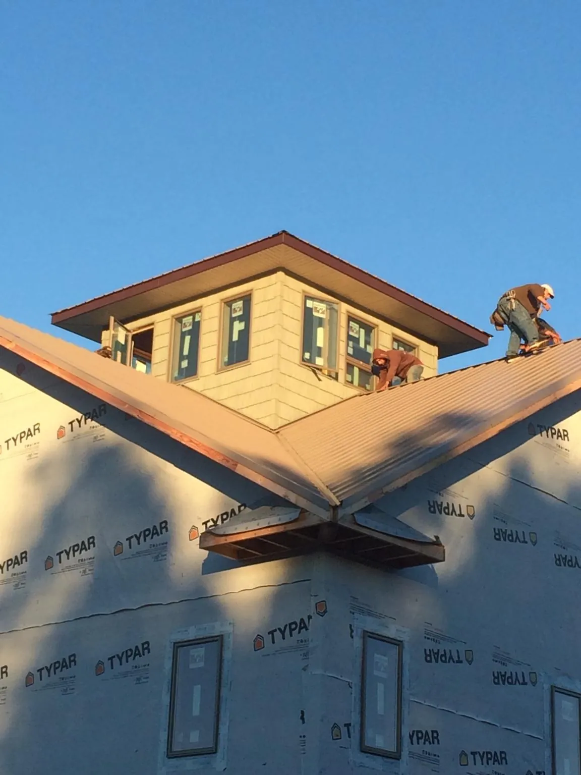 Roofers working around a rooftop cupola on a new metal roof at sunset — Roof Waterproofing in Schiller Park by Roofing Brothers